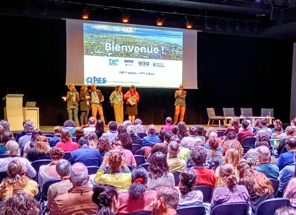Photo du public regardant vers l'écran pendant le colloque QPES