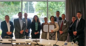 Photo de groupe des directrices et directeurs des écoles et de la directrice générale de l'IMT. La directrice générale tient et présente la charte signée