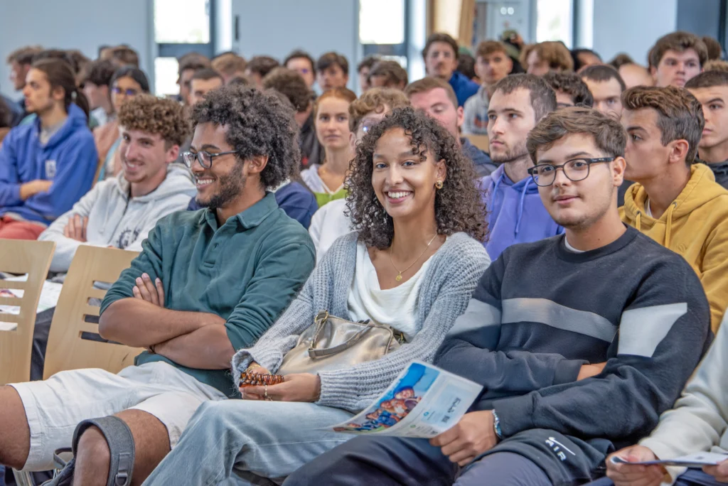 Groupe d'élèves d'IMT Atlantique lors de la rentrée en septembre, zoom sur trois élèves assis en amphi, souriant.